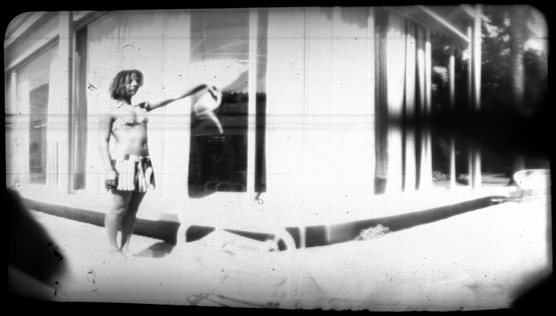 Fotografia em preto e branco com figura humana diante de uma fachada e distorção nas bordas.