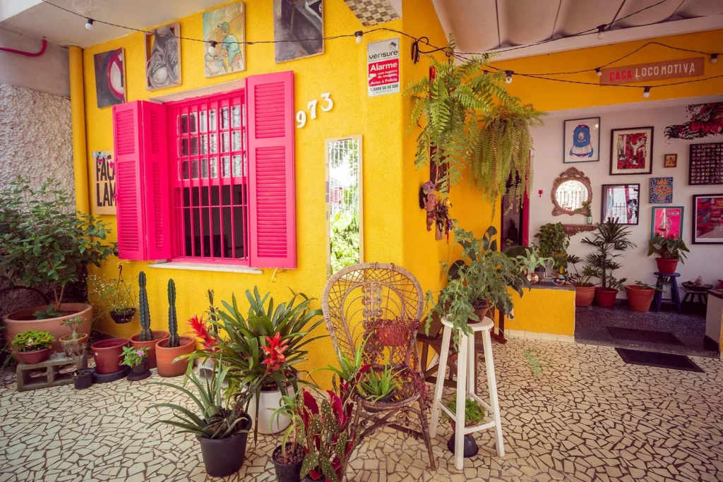 Fachada amarela com janela rosa e plantas
