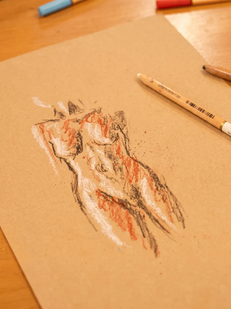 Desenho de figura humana sobre papel ao lado de um lápis.